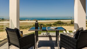 A balcony with wicker chairs, a table with a magazine, and a lantern. - The Ionian Sea and Sunset View Villa (Minia)