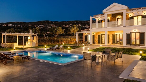 A modern villa with a swimming pool, outdoor seating, and a well-lit patio area. - The Ionian Sea and Sunset View Villa (Minia)