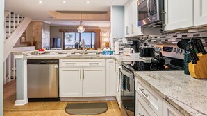 A modern kitchen with white cabinetry, stainless steel appliances, and a large island. - Oceanfront 3BR Luxe New Rental (St. Augustine)