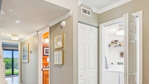 A hallway with a view to a balcony, a kitchen area, and a laundry room. - Oceanfront 3BR Luxe New Rental (St. Augustine)