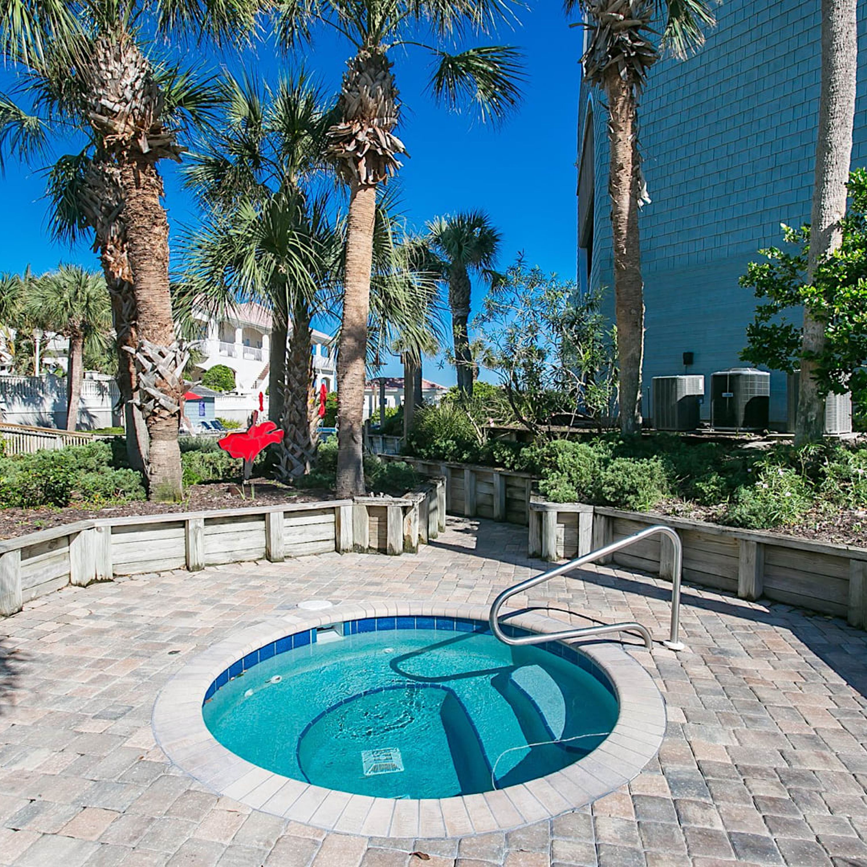 A circular pool with a metal ladder, surrounded by palm trees and a wooden fence.