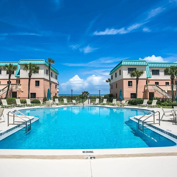 Relax by the resort pool surrounded by lounge chairs and umbrellas.