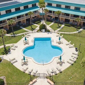 Relax by the hotel's central pool surrounded by a patio with lounge chairs and umbrellas.