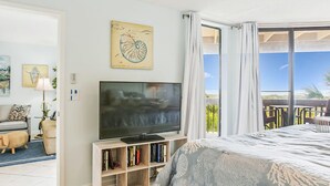 Un dormitorio con una cama grande, un televisor en un estante de madera, una estantería y vistas al exterior.