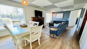 Un salon moderne comprenant un coin repas, un canapé bleu et un téléviseur à écran plat.