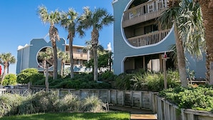 A modern building with a unique curved architecture, surrounded by palm trees and a wooden deck. - Pool Oasis Sunny Retreat Near St Augustine (St. Augustine)
