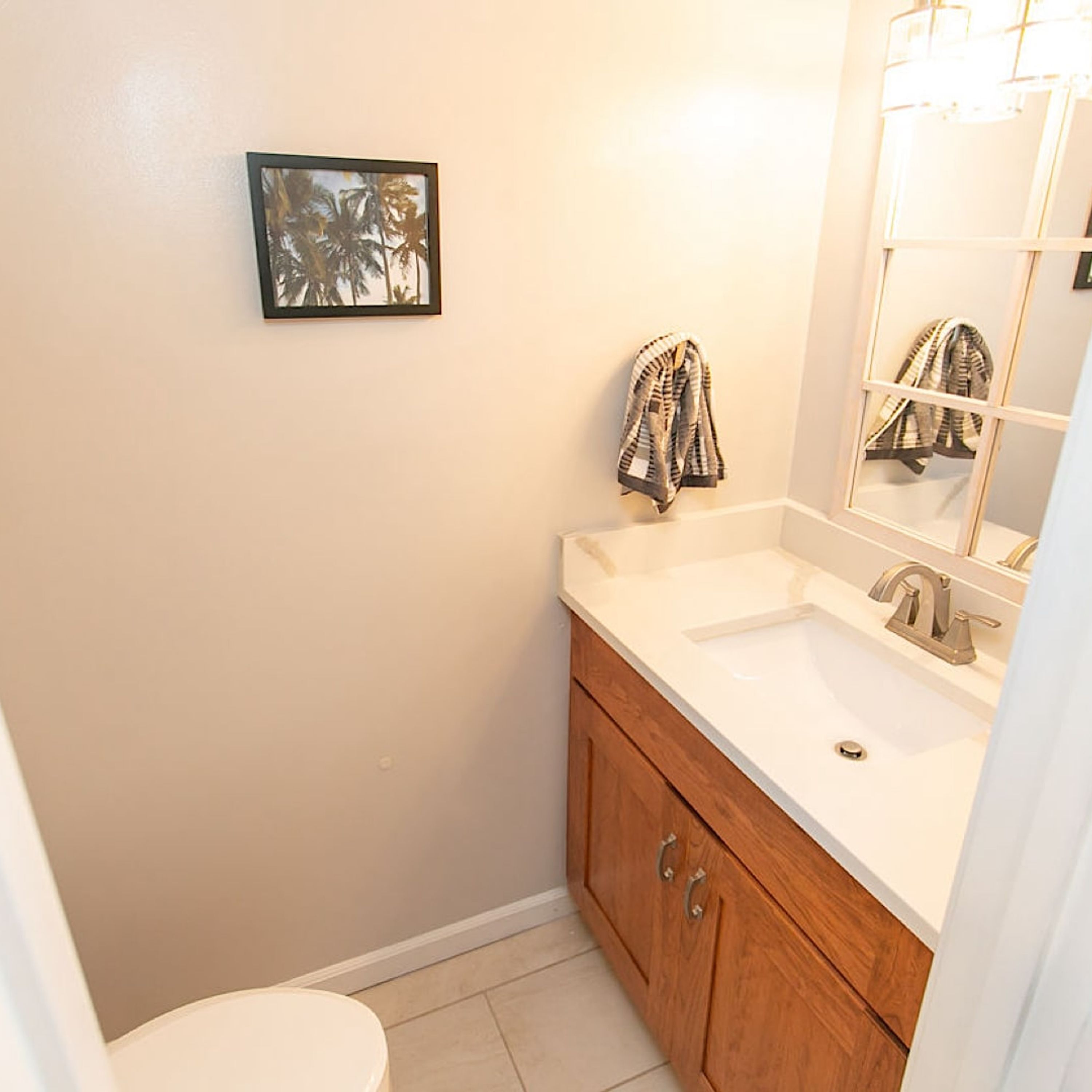 A bathroom with a white sink, wooden vanity, and a mirror.
