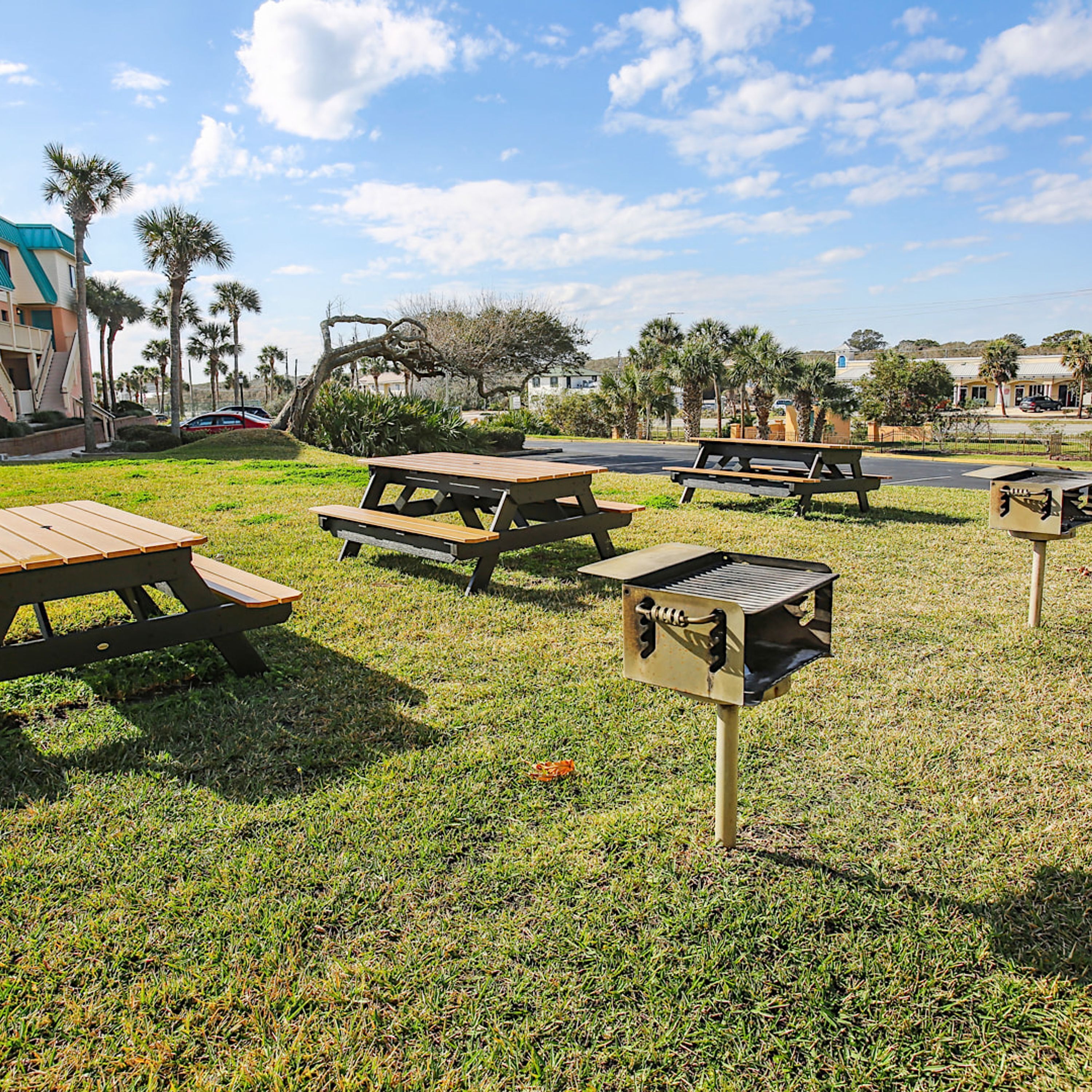 A grassy area with picnic tables and barbecue grills.