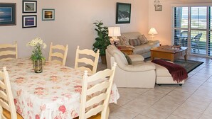 A living room with a dining table, chairs, a sofa, a coffee table, and a plant. - Sea Haven 221 Oceanfront Pool Comfort (St. Augustine)