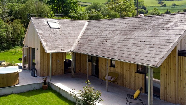 A wooden building with a sloped roof, a covered patio area with seating, and a small pool. - Sunnybrook in Shaldon (Teignmouth)