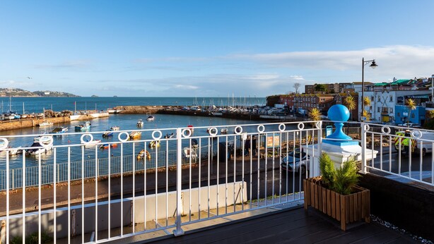 A coastal marina with boats docked, a white fence, and a view of the sea. - Quayside View in Paignton (Paignton)