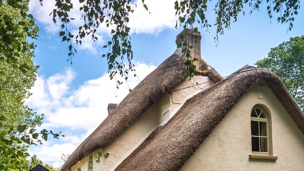 A traditional thatched-roof house with a stone foundation, a small window, and a door. - Weeke Brook in Chagford (Newton Abbot)