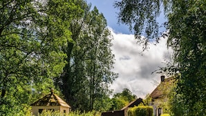 A rural setting with a gravel path leading to a thatched-roof house surrounded by lush greenery. - Weeke Brook in Chagford (Newton Abbot)