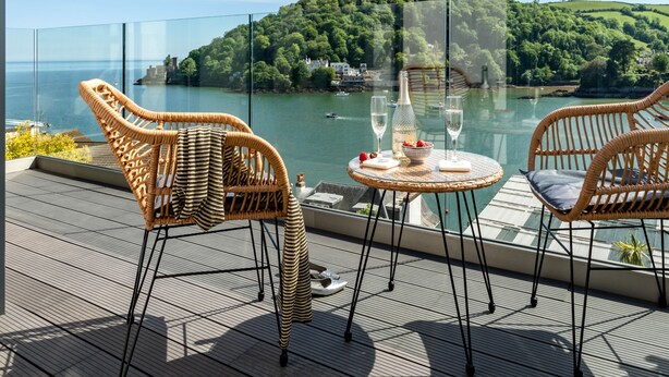 A terrace with wicker chairs and a table, overlooking a lake and a forested hill. - Two Guns in Kingswear (Dartmouth)