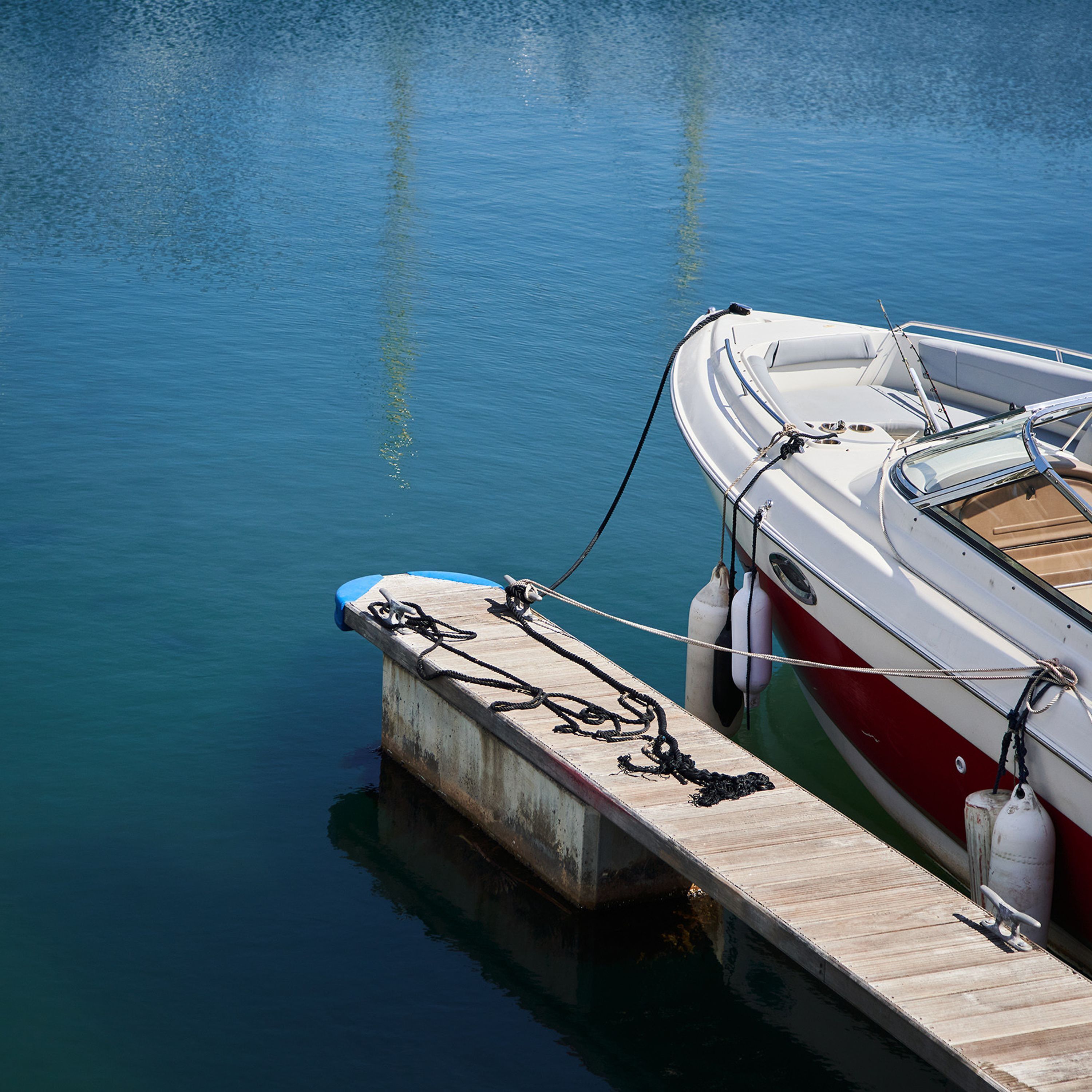 A wooden dock with a boat tied to it.