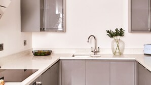 Een moderne keuken met een ingebouwde vaatwasser, een roestvrijstalen spoelbak en een houten vloer.