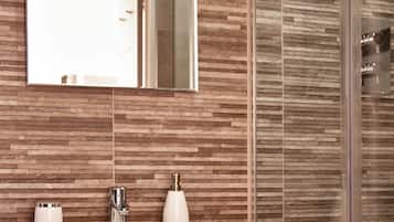 A bathroom with a rectangular sink, a mirror, and a shower with a glass door.