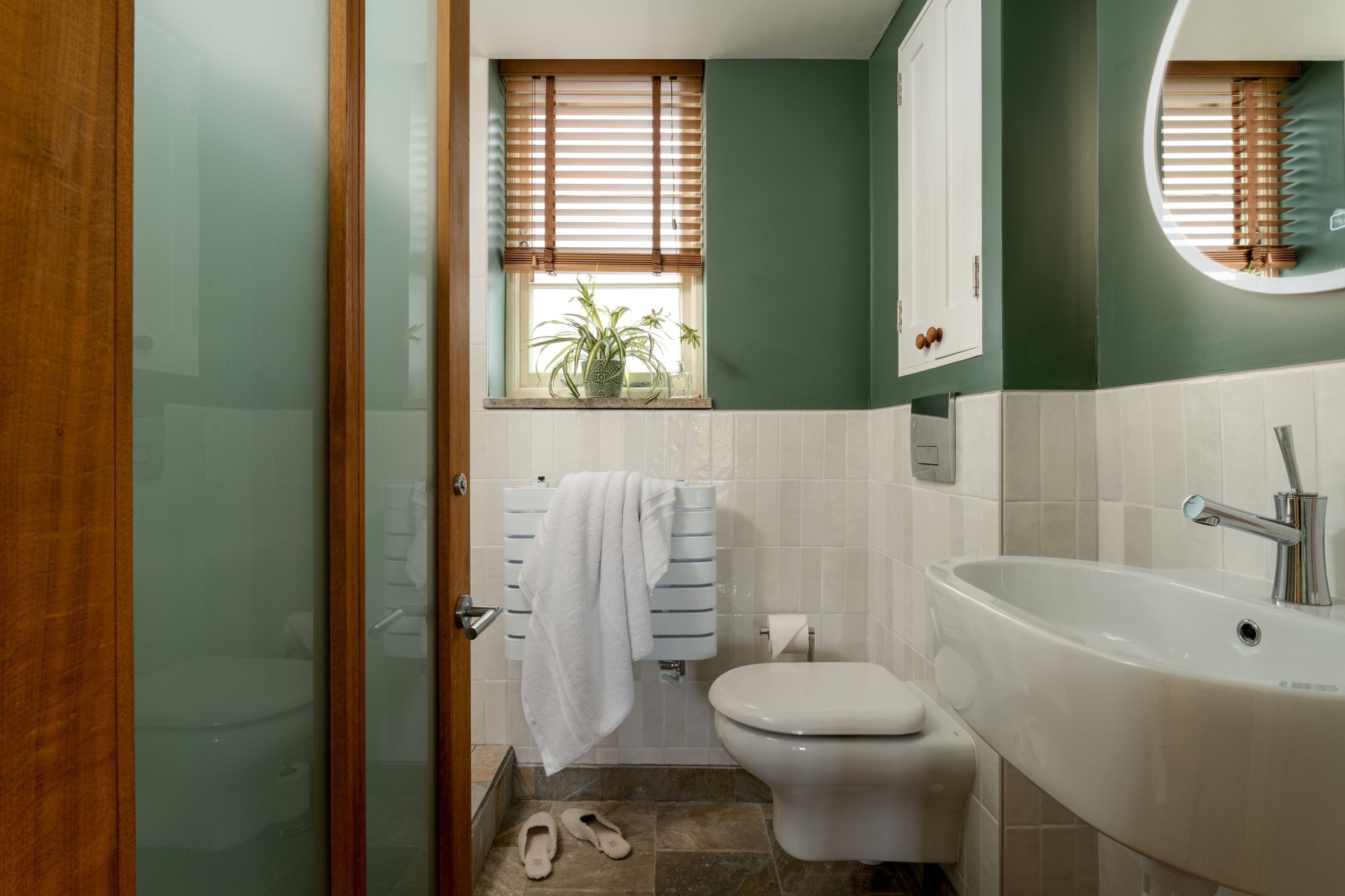 Un baño con inodoro, lavamanos y ventana con persianas.