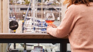 A person holding a wine glass, overlooking a marina with boats and buildings in the background. - Harbour Breeze in Torquay (Torquay)