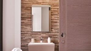 A modern bathroom with a wooden wall, a mirror, a sink, and a towel on the bed. - Harbour Breeze in Torquay (Torquay)