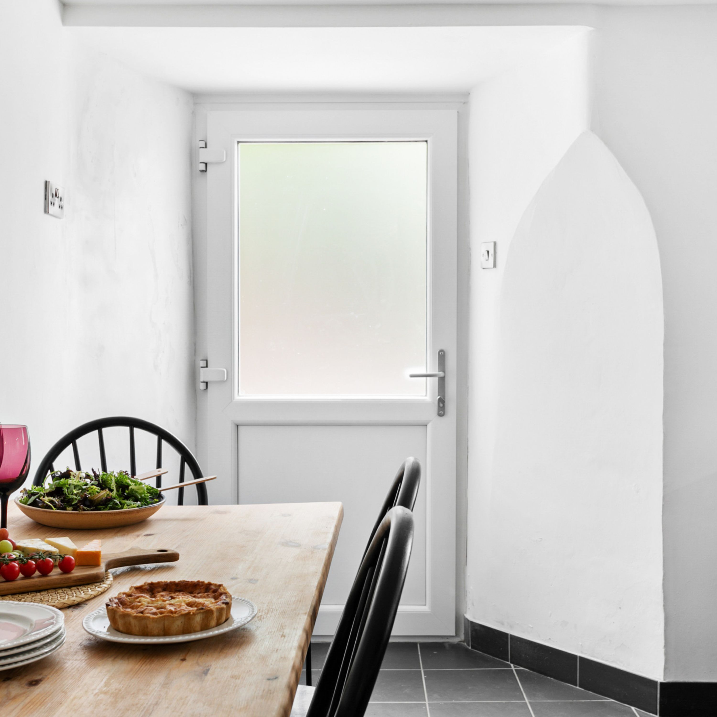 A dining area with a table set for two, a bowl of salad, a plate of food, and a pie on the table.