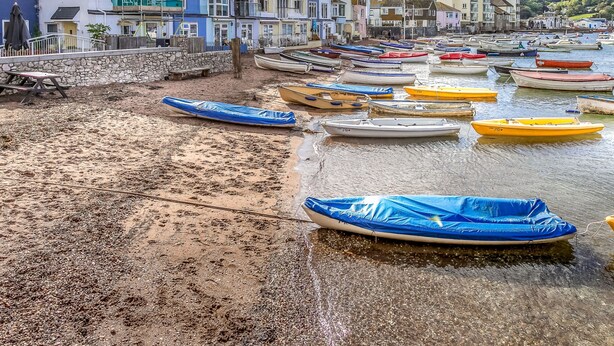 Eine Küstenstadt mit bunten Häusern und einem Sandstrand mit Booten.