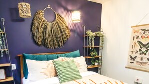 A bedroom with a bed, a headboard, a wall-mounted plant shelf, and a wall art piece.