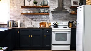 A modern kitchen with dark cabinets, a white stove, and a brick backsplash.