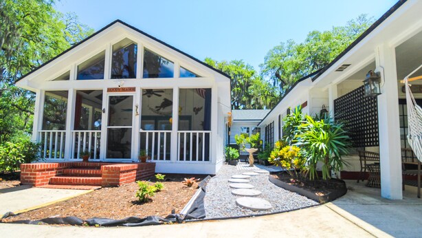 A two-story house with a porch, a small garden with stepping stones, and a pathway leading to the entrance.