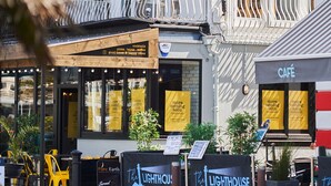 Une vue d’une rue bordée de nombreux commerces, notamment un restaurant de fruits de mer, un café et un bar.