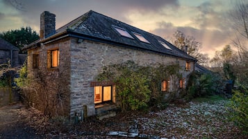 A stone house with a sloped roof, two skylights, and a chimney.