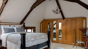 A bedroom with a wooden bed frame, a large window, and a mirror. - Old Coach House in Berry Pomeroy (Totnes)