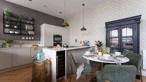 A modern kitchen with a central island, built-in appliances, and a dining area with green upholstered chairs. - Cathedral Yard in Exeter (Exeter)
