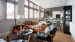 A modern living room with a leather sofa, a dining area, and a kitchen in the background. - Cathedral Yard in Exeter (Exeter)