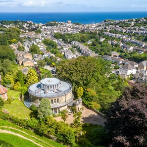 A coastal town with a prominent round building featuring a central dome and a surrounding garden.