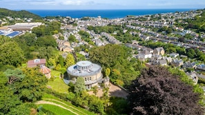 A coastal town with a prominent round tower surrounded by lush greenery and residential buildings.