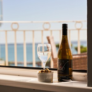 A bottle of wine and a glass on a windowsill with a view of the sea. - Bayfort Sea Studio in Torquay (Torquay)