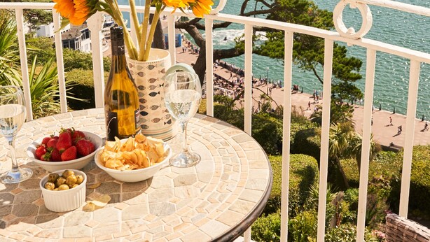A balcony with a table set for dining, overlooking a marina with boats and a coastal view. - Bayfort Sea Studio in Torquay (Torquay)