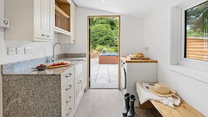 Cocina moderna con encimeras de granito, horno integrado y vistas a un jardín y jacuzzi a través de una puerta abierta.