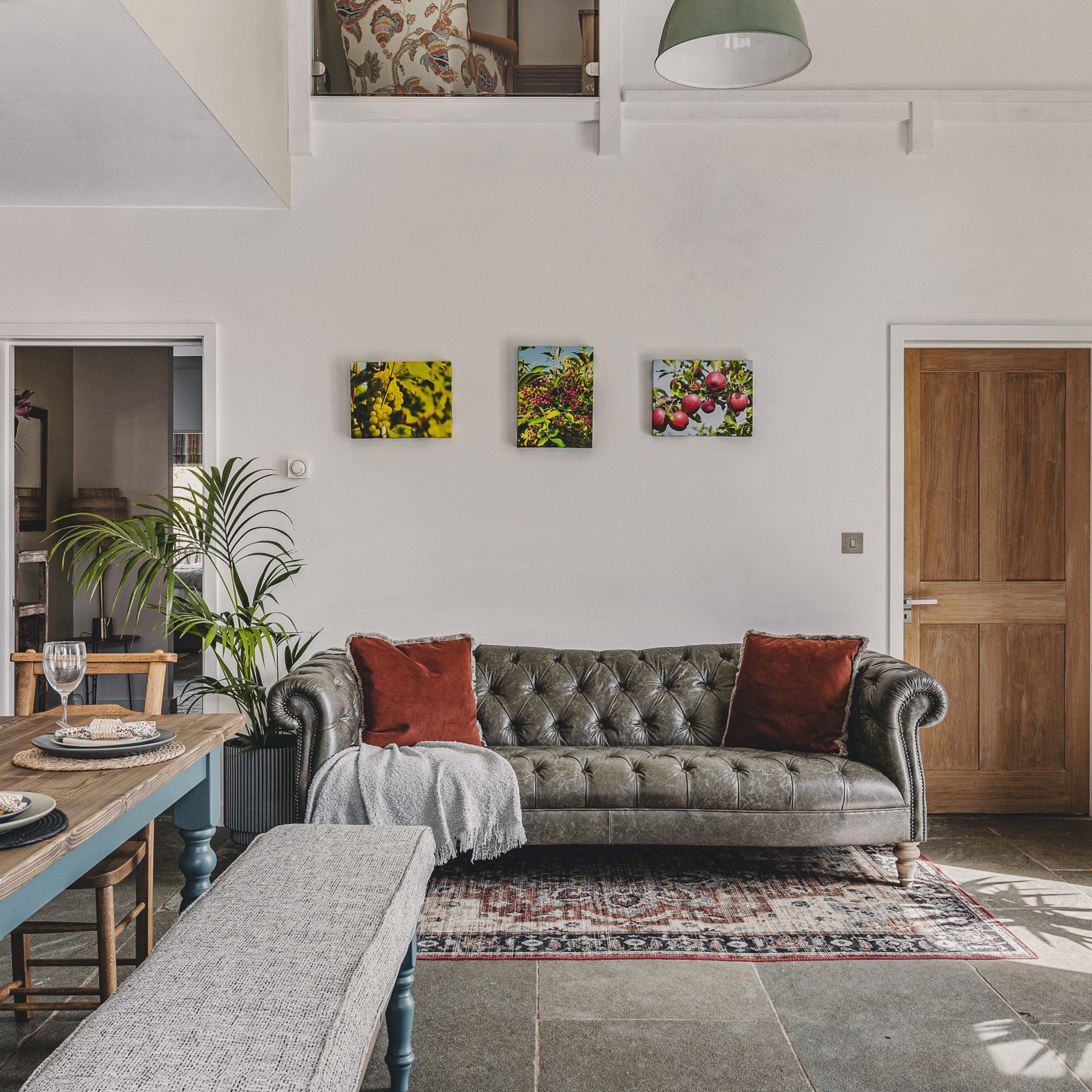 A cozy living room with a leather sofa, a dining table with chairs, and a large window.