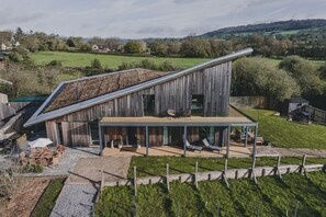 A modern house with a sloped roof, a covered patio, and a view of the surrounding countryside.