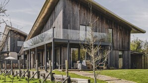 A large wooden building with a sloped roof and a covered patio area.