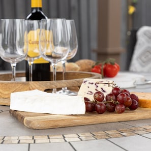 A wooden board with cheese, grapes, and bread, accompanied by wine glasses and a bottle. - Greenacre in Bishopsteignton (Teignmouth)