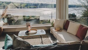 Una habitación acogedora con un amplio ventanal que ofrece vistas a un río y un paisaje lejano.