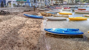 Un pueblo costero con edificios coloridos y una playa de arena con barcos.