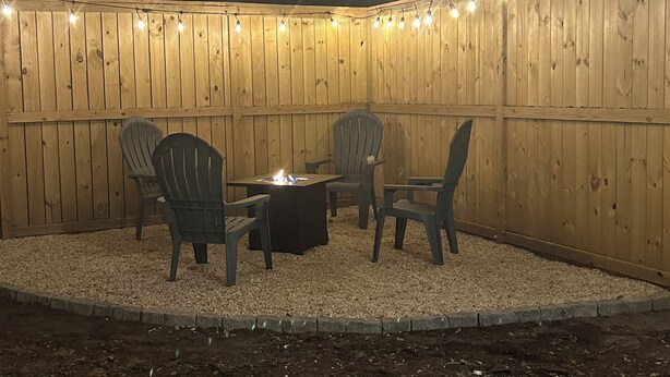 An outdoor patio with wooden walls, string lights, and a fire pit. - A getaway on the Marsh! (Murrells Inlet)