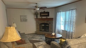 A living room with a fireplace, a ceiling fan, a lamp, and a couch. - A getaway on the Marsh! (Murrells Inlet)