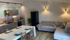 Une cuisine moderne avec une table et des chaises, un canapé gris et un meuble noir.