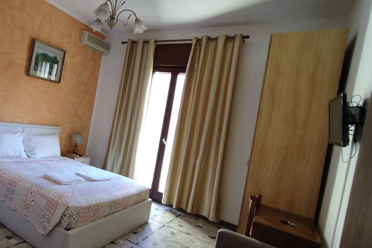 Une chambre à coucher comprenant un lit, des tables de chevet, une chaise, un bureau et un téléviseur.