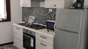 Eine moderne Küche mit Gasherd, Backofen, Kühlschrank und Kaffeemaschine auf der Arbeitsfläche.